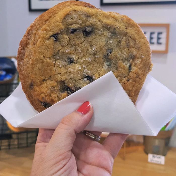 A lemon blueberry cookie held in a paper sleeve